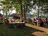 Photo prise à La Dérivée représentant des personnes attablées dans un parc arborisé.